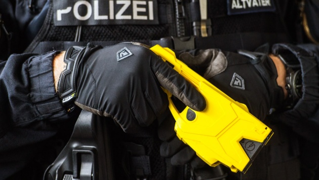 Ein Polizist hält eine grell gelbe Elektroschockpistole in den Händen.