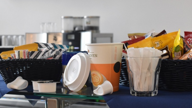 To-go-Kaffebecher, Plastikdeckel, portionierte Sahne und Zucker liegen auf einem Tresen in der Cafeteria vor dem Plenarsaal.